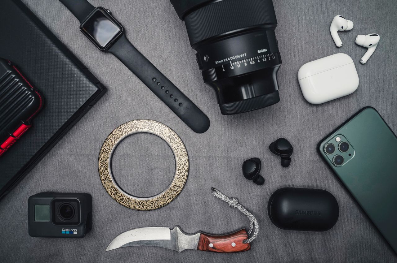 Flat lay of tech gadgets and personal accessories including camera and smartwatch.
